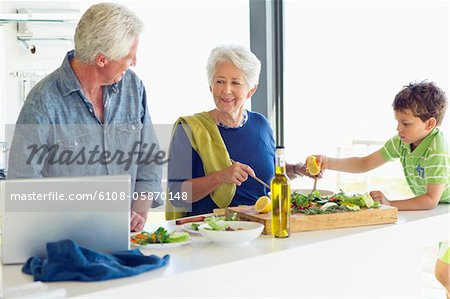 Senior couple avec leur petit-fils, préparer le repas dans une cuisine