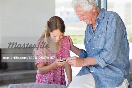 Man showing a message from a mobile phone to his granddaughter