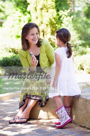 Woman holding a mobile phone and looking at her granddaughter