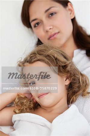 Portrait d'une jeune femme couchée avec sa fille, enveloppée dans une serviette blanche