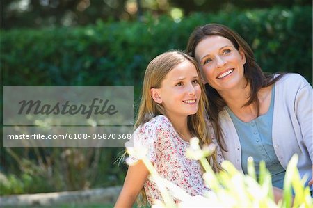 Belle petite fille et sa mère assis ensemble dans le jardin