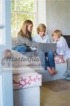 Children and their mother using laptop at house