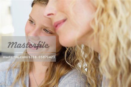 Close-up of happy daughter sitting with mother