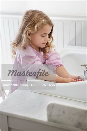 Adorable petite fille, se laver les mains dans l'évier de salle de bains