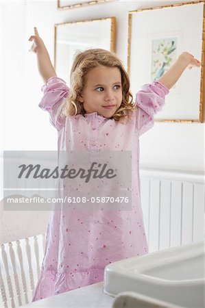 Adorable petite fille debout avec les bras levés devant un évier de salle de bains