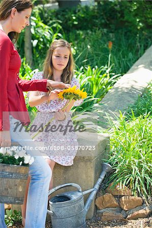 Cute little girl and mother holding sunflower outdoors
