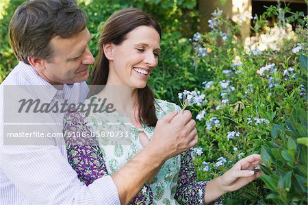 Happy mature couple looking at flowers in a garden