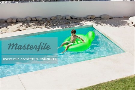 Boy sitting on inflatable ring in swimming pool