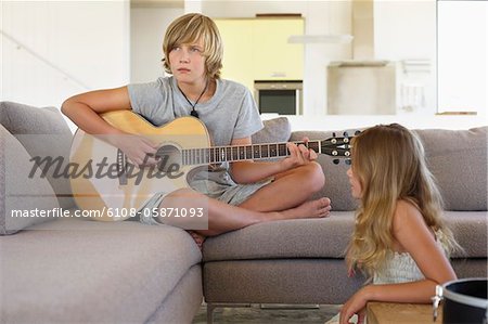Fille regardant un frère joue une guitare