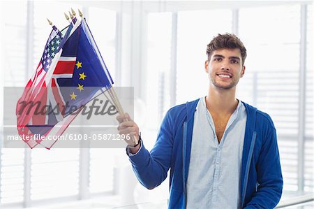 Portrait d'un homme tenant des drapeaux de différents pays dans un aéroport