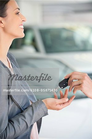 Side profile of a young woman taking car key in showroom