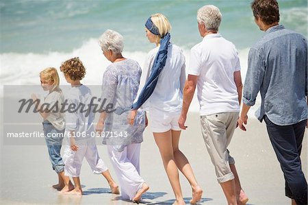 Multi génération famille marchant en ligne sur la plage