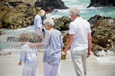 Multi generation family collecting shell on the beach