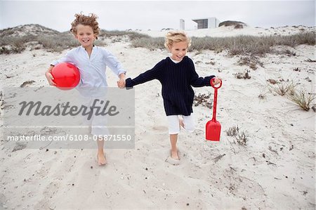 Children holding toys and running on sand