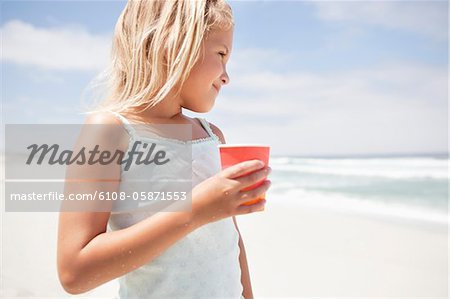 Girl holding a disposable glass on the beach
