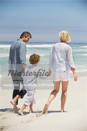 Rear view of a couple walking with their son on the beach