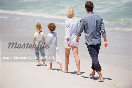 Couple avec deux enfants marchant sur la plage