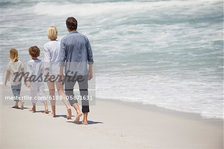 Couple avec deux enfants marchant sur la plage