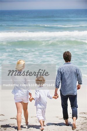 Couple avec leur fils marchant sur la plage