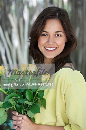 Portrait of a young woman holding bunch of yellow flowers