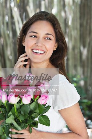 Happy young woman holding bunch of colorful roses