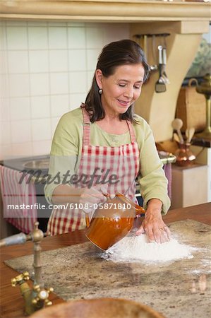 Smiling senior woman pouring water in flour