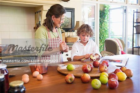 Grandmother and little boy peeling an apple at home