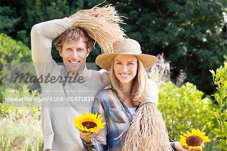 Portrait d'un couple en épouvantail pose dans un champ