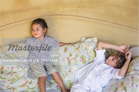 Cute siblings lying on couch at home