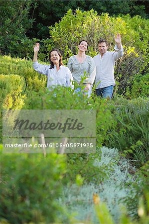 Mature couple walking with their mother and waving hand in a garden