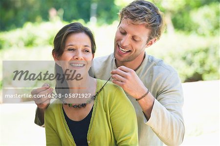 Man fastening mom's necklace outdoors