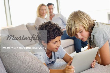 Brothers using a digital tablet with their parents looking at them