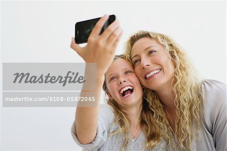 Fille avec sa photo prise de mère d'eux-mêmes avec un téléphone mobile
