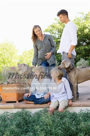 Family having a good time outside house with two dogs