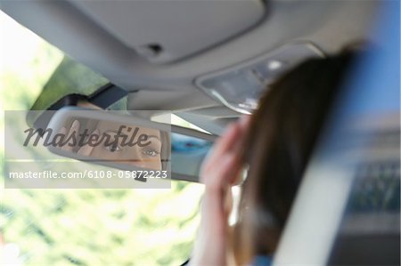 Reflection of a young woman eyes in rear-view mirror