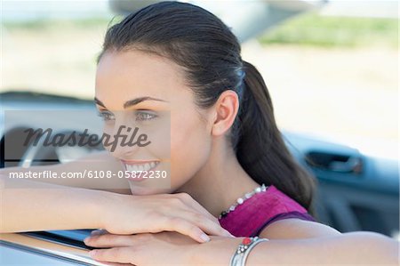 Beautiful young woman leaning on car window