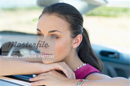 Jeune femme accoudée à la fenêtre de la voiture