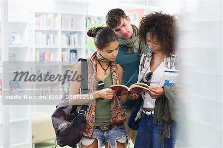 Studenten, die in einer Bibliothek ein Buch zu lesen