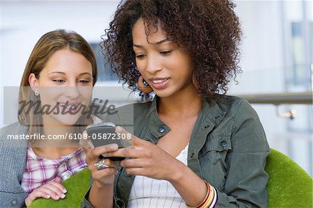 Smiling women using mobile phone in university