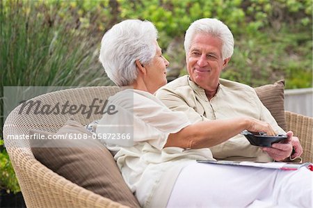 Senior couple sitting in a wicker couch eating food