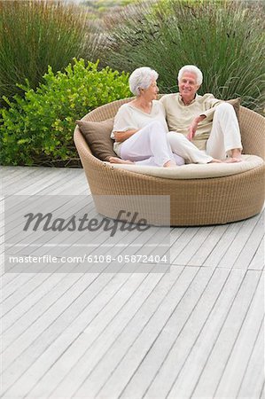 Senior couple sitting in a wicker couch