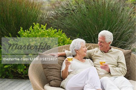 Senior couple sitting in a wicker couch and smiling