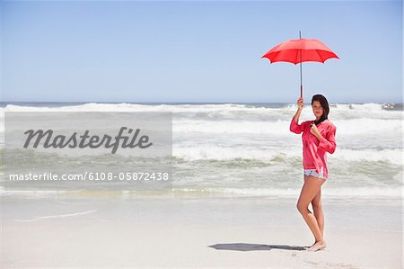 Femme debout sur la plage avec un parasol