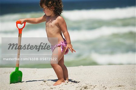 Girl playing with a sand shovel on the beach
