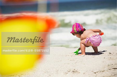 Vue arrière d'une fille de creuser avec une pelle à sable sur la plage