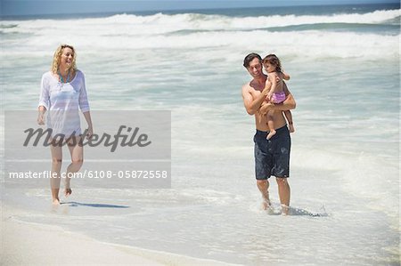 Couple walking on the beach with their daughter