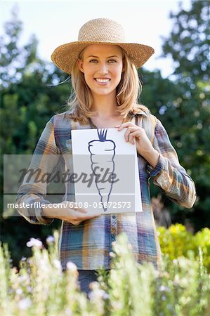 Portrait of a young woman showing carrot painting in a field