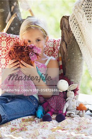 Contemplative fillette tenant des jouets dans la maison de l'arbre Contemplative fillette tenant des jouets dans la maison de l'arbre