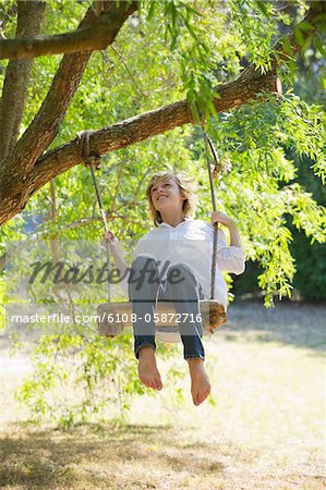 Joyeux petit garçon se balançant sur arbre