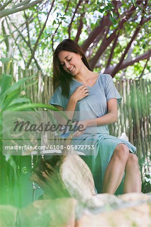 Young woman pouring aromatherapy oil in bathtub